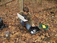 Dr. Rob Rossi kneels on leaf-covered ground.