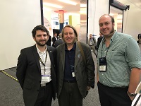 Three men stand side by side smiling.